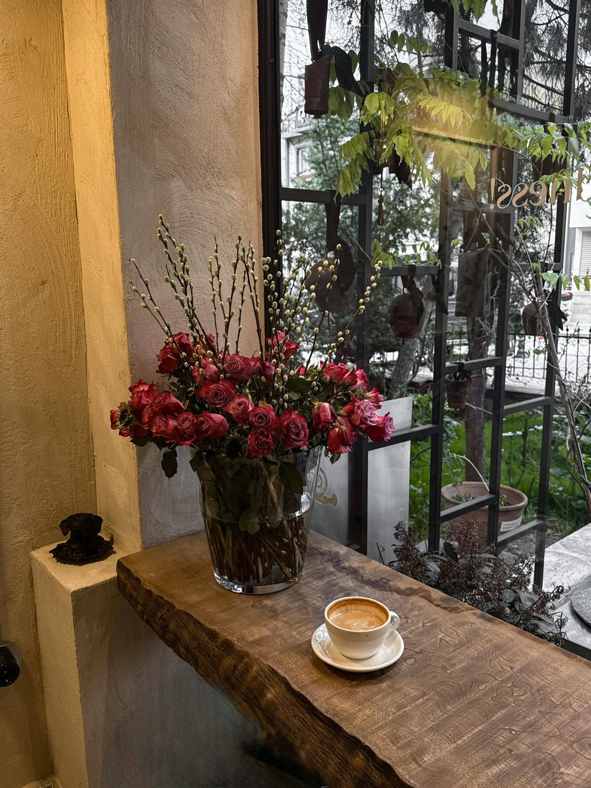 Warm cafe scene with flowers and a cappuccino by the window, perfect for a relaxing afternoon.
